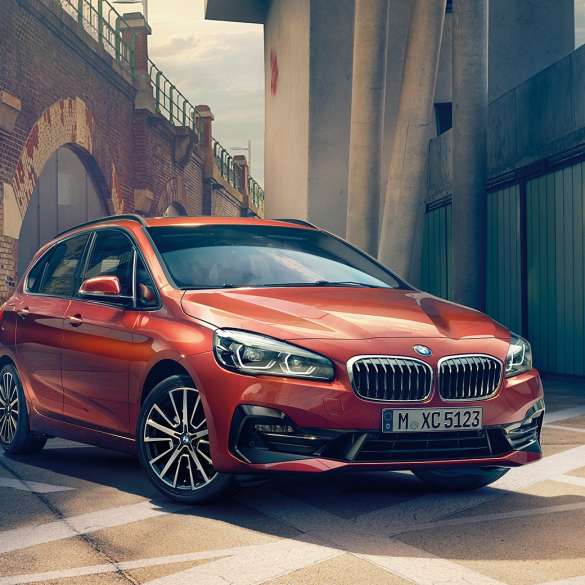 Ulkopuoli, BMW 2-sarjan Active Tourer BMW 2-sarjan Active Tourer F45 Facelift 2018 metalliväri Sunset Orange, kolmen neljäsosan näkymä kujalle pysäköidyn auton keulasta