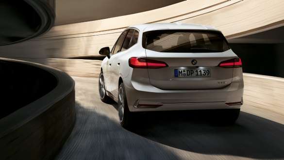 Perän dynaaminen muotoilu, BMW 2-sarjan Active Tourer U06 2021 BMW 2-sarjan Active Tourer U06 2021 metalliväri Mineral White, näkymä pysäköintitalon kierrerampissa ylöspäin ajavan auton perästä
