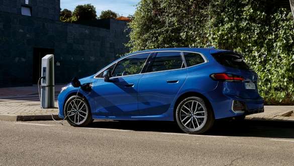 BMW 2-sarjan Active Tourer 230e Plug-in Hybrid U06 2021 pysäköitynä lataustolpan vieressä BMW 2-sarjan Active Tourer 230e Plug-in Hybrid U06 2021 metalliväri M Portimao Blue, sivukuva lataustolpan viereen pysäköidystä autosta