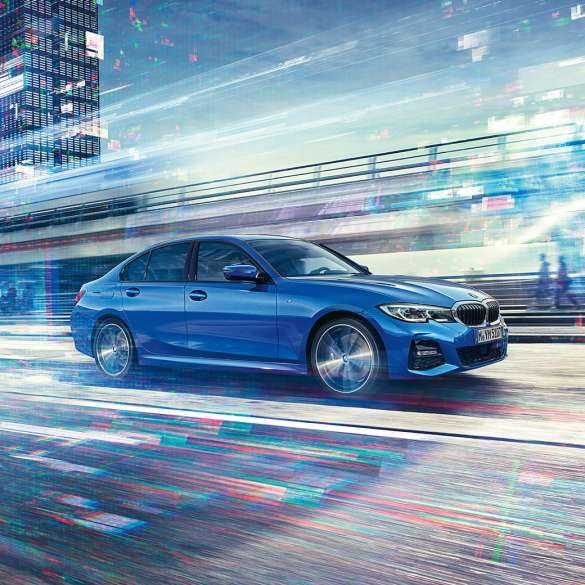 Liikkuva BMW 3-sarjan Sedan sivultapäin. Sivukuva liikkuvasta BMW 3-sarjan Sedanista päivänvalossa suurkaupunkiympäristössä.