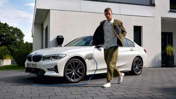 Plug-in hybrid, BMW 3-sarjan Sedan 2021 G20, kolmen neljäsosan näkymä latauksessa olevan auton keulasta Plug-in hybrid, BMW 3-sarjan Sedan 2021 G20, kolmen neljäsosan näkymä latauksessa olevan auton keulasta yhdessä mallin kanssa