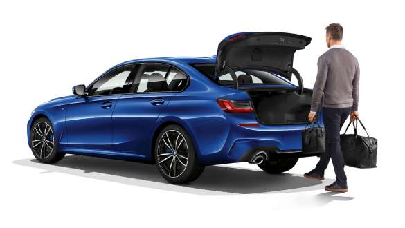 BMW 3-sarjan Sedan, takaluukun automatiikka. Kolmeneljäsosakuva BMW 3-sarjan Sedanin perästä, kuljettaja avaa takaluukun vain jalkaa heilauttaen.