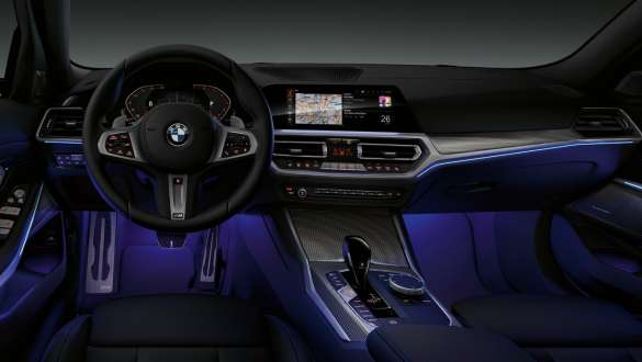 BMW 3-sarjan Sedan (G20), Ambient-tunnelmavalaistus. Kuva BMW 3-sarjan Sedanin (G20) kuljettajan puoleisesta ohjaamosta, jossa Ambient-tunnelmavalaistuksen siniseksi valaisema jalkatila.