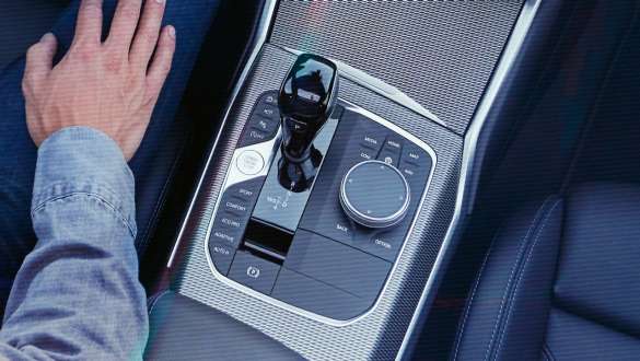 BMW 3-sarjan Sedan (G20), Steptronic Sport -vaihteisto. Lähikuva lintuperspektiivistä BMW 3-sarjan Sedanin (G20) keskikonsolista, jossa vaihevivun nuppi ja Steptronic Sport -vaihteisto.