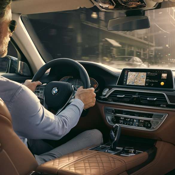 BMW 7-sarjan Sedanin Connectivity-ominaisuudet BMW 7-sarjan Sedan: Mies istuu BMW:ssä ja käyttää Connectivity-ominaisuuksia