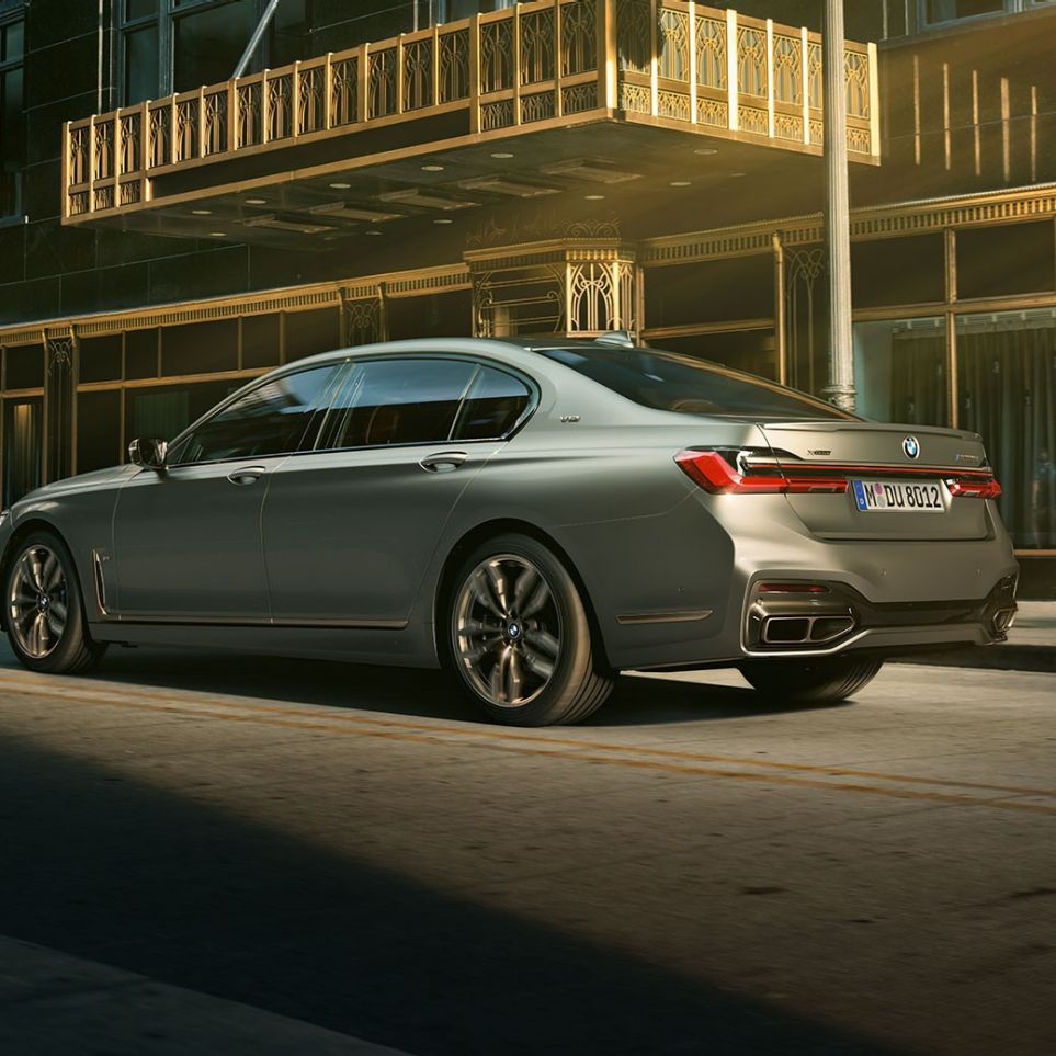 BMW M760Li xDrive Sedan ja V12-moottori BMW M760Li xDrive Sedan, sivunäkymä perästä pilvenpiirtäjien edessä kaupunkimaisemassa