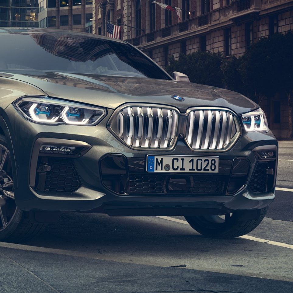 BMW X6 M50i pysähtyneenä BMW X6 M50i, 3/4-näkymä edestä auton ollessa pysähtyneenä kaupunkinäkymän edessä