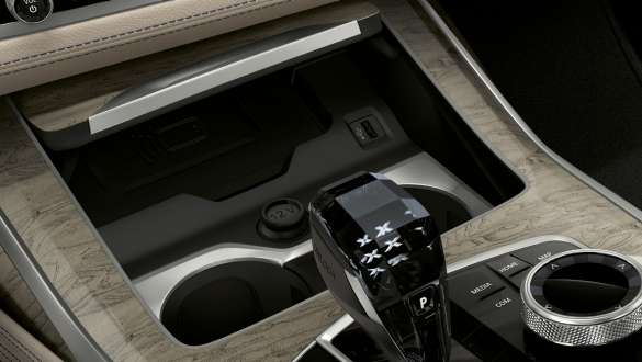 BMW X7 M -auton lämpötilasäädöllä varustetut juomatelineet BMW X7 M -auto, sisätila, lähikuva keskikonsolista, fokus lämpötilasäädöllä varustetussa juomatelineessä, G07