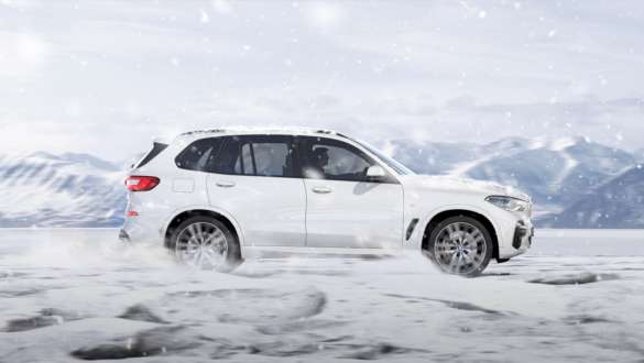Ajotila xSnow, BMW X5 Ajotila xSnow, BMW X5 G05 2018 metalliväri Mineral White, sivunäkymä lumella ajavasta autosta
