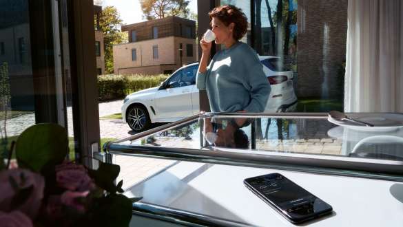 Remote Software Upgrade, BMW X5 Nainen juo kupillisen kahvia sillä välin, kun hänen BMW X5 -autonsa ohjelmisto päivittyy Remote Software Upgraden kautta, G05 2018