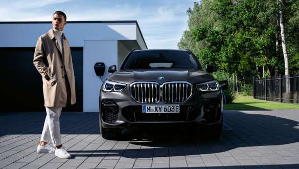 Plug-in hybrid BMW X5 xDrive45e G05, näkymä keulasta autotallin edessä yhdessä mallin kanssa Plug-in hybrid BMW X5 xDrive45e G05, näkymä keulasta autollin edessä yhdessä mallin kanssa