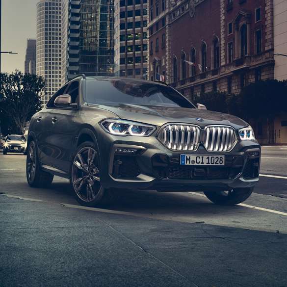 BMW X6, adaptiivinen M-alusta Professional. BMW X6, 3/4-näkymä edestä kaupunkinäkymän edustalla.