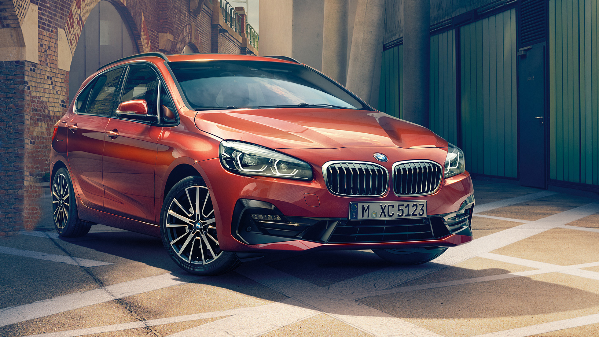 Ulkopuoli, BMW 2-sarjan Active Tourer BMW 2-sarjan Active Tourer F45 Facelift 2018 metalliväri Sunset Orange, kolmen neljäsosan näkymä kujalle pysäköidyn auton keulasta