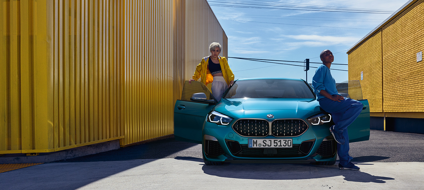 BMW 2-sarjan Gran Coupé F44, näkymä edestä BMW 2-sarjan Gran Coupé F44 metalliväri Snapper Rocks Blue, näkymä edestä autosta, jossa kaksi henkilöä ja ovet avattuina