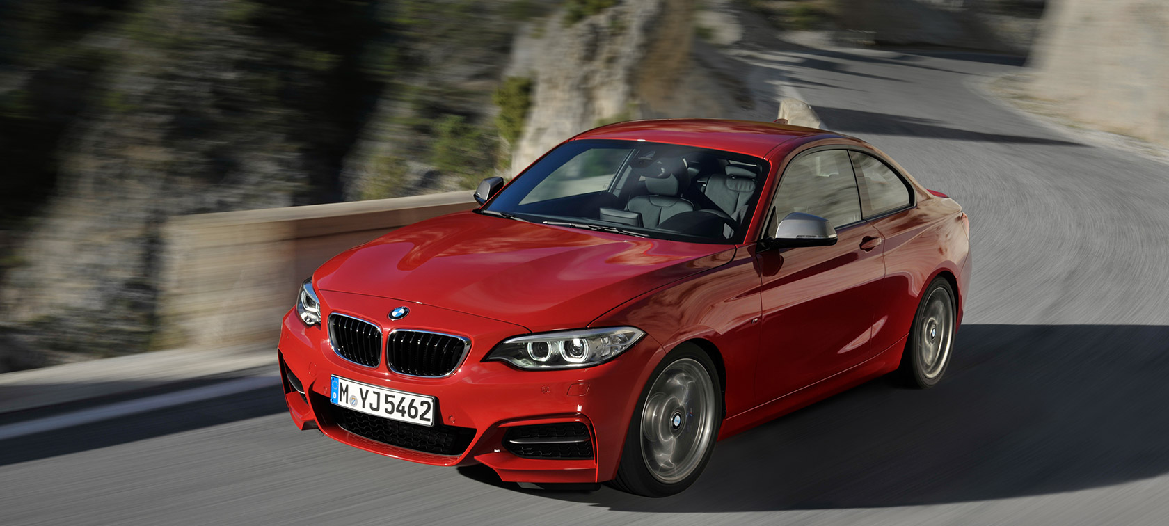 BMW 2-sarja, kolmen neljäsosan näkymä maisematiellä ajavan auton keulasta BMW 2-sarjan mallit, kolmen neljäsosan näkymä maisematiellä ajavan BMW-auton keulasta