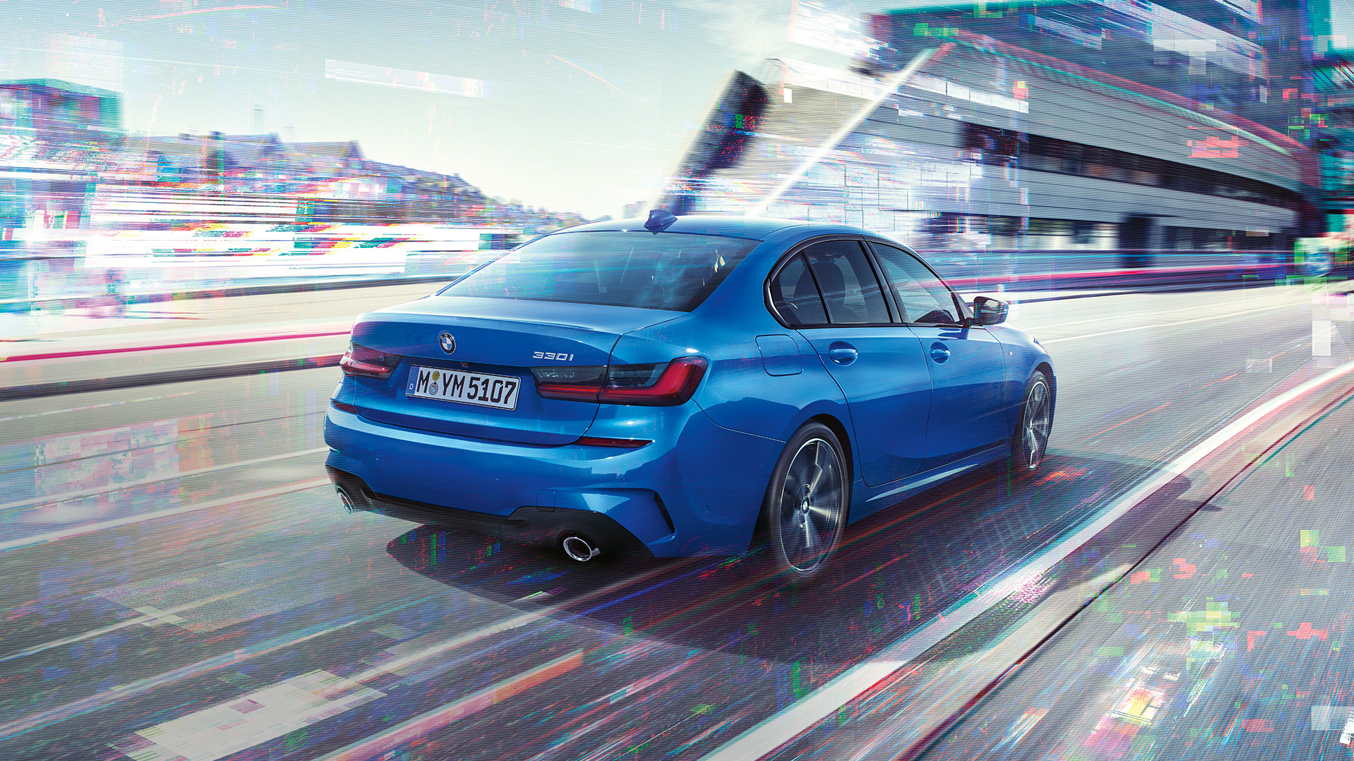 BMW 3-sarjan Sedan, sivukuva perästä. Kolmeneljäsosakuva BMW 3-sarjan Sedanin perästä päivänvalossa suurkaupunkiympäristössä.