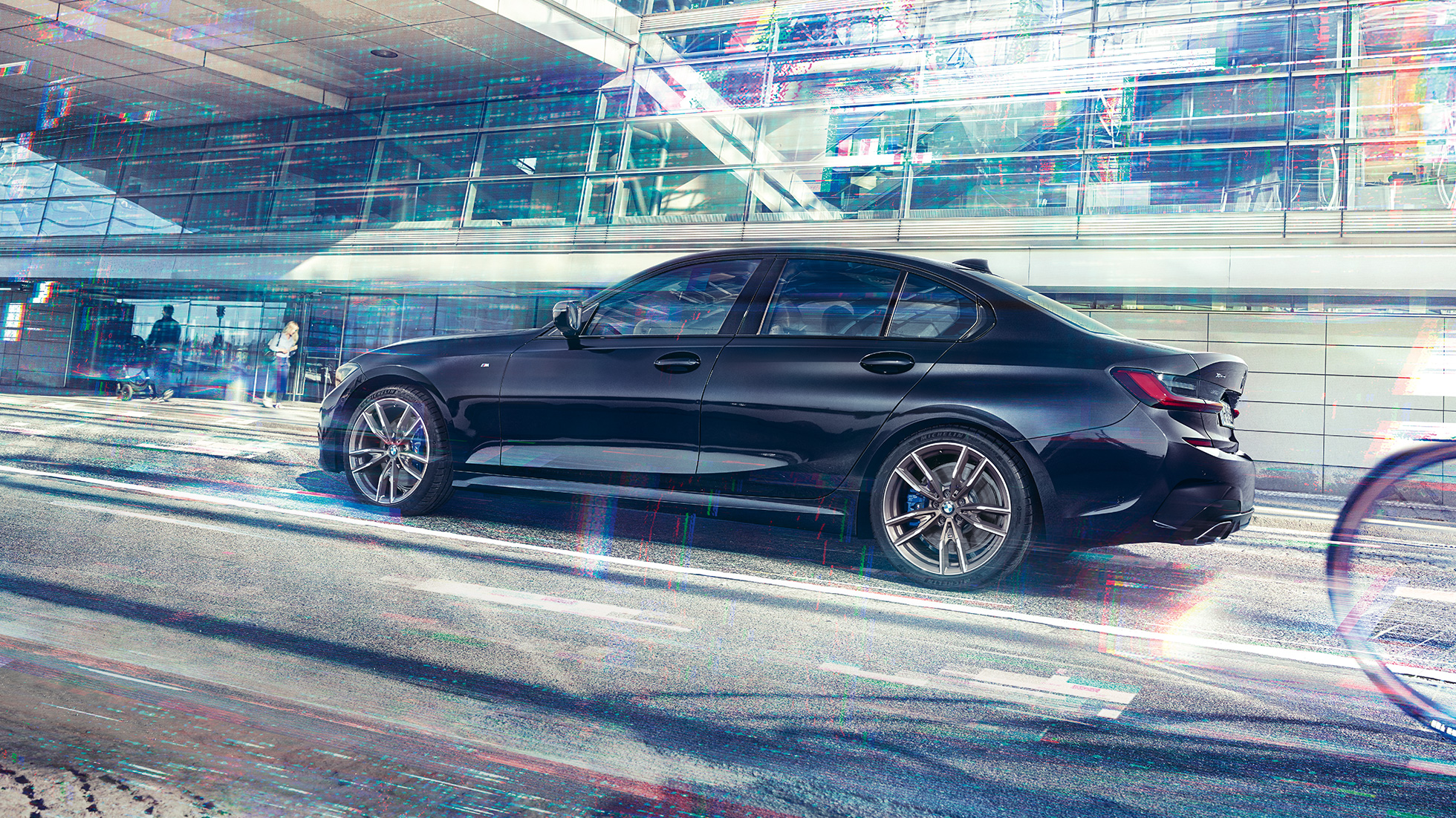 BMW 3-sarjan Sedan, BMW M340i xDrive -malli. Sivukuva mallista BMW M340i xDrive paikallaan suurkaupunkirakennuksen edessä.