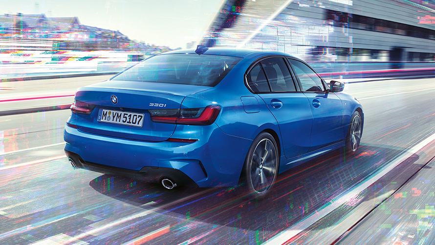 BMW 3-sarjan Sedan (G20), sivukuva perästä. Kolmen neljäsosan näkymä BMW 3-sarjan Sedanin (G20) perästä päivällä kaupunkimaisemissa.