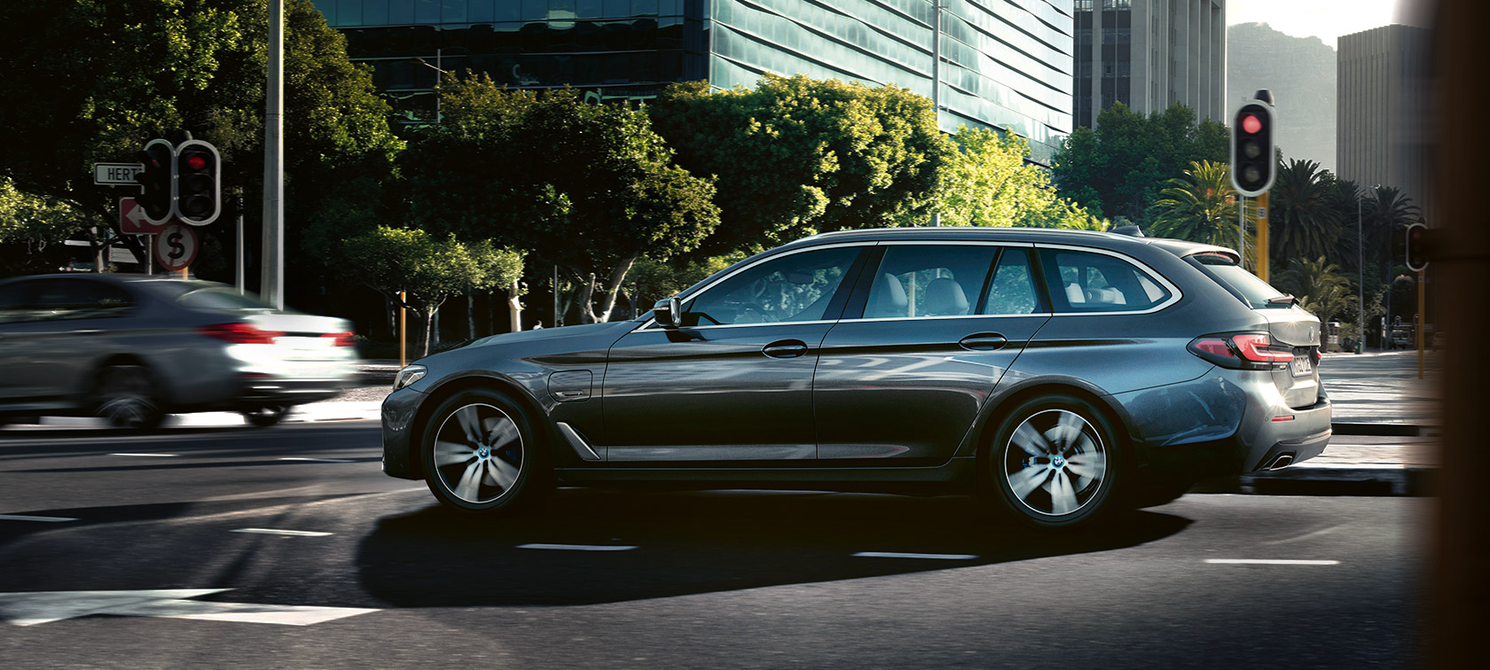 BMW 530e Touring G31 LCI metallivärissä Sophisto Grey, pysähtyneenä rakennuksen edessä BMW 530e Touring G31 LCI metallivärissä Sophisto Grey, pysähtyneenä rakennuksen edessä