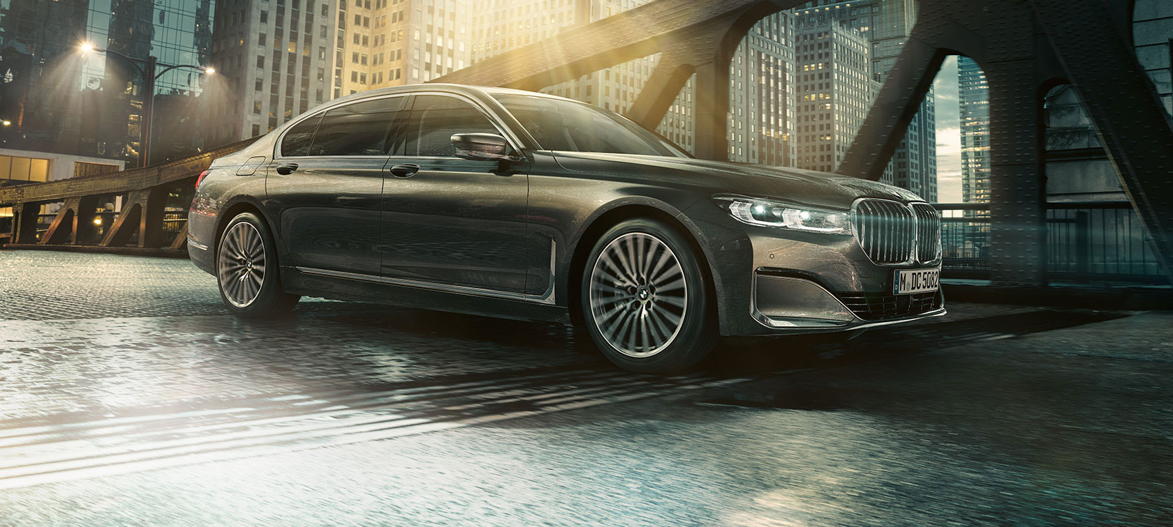 BMW 7-sarjan Sedan, näkymä sivulta BMW 7-sarjan Sedan seisoo sivulta nähtynä, ovi auki valaistun hotellin edessä