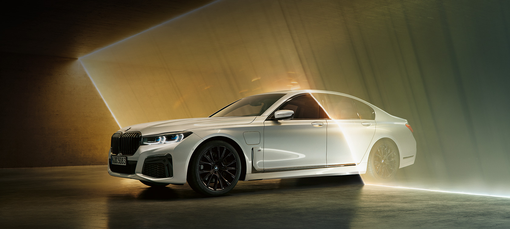 BMW 7-sarjan Sedan, valkoinen, kolme neljäsosan näkymä etuosasta BMW 7-sarjan Sedan: Kuva, jossa näkyy kolme neljäsosaa valkoisen BMW:n etuosasta valon ympäröimänä