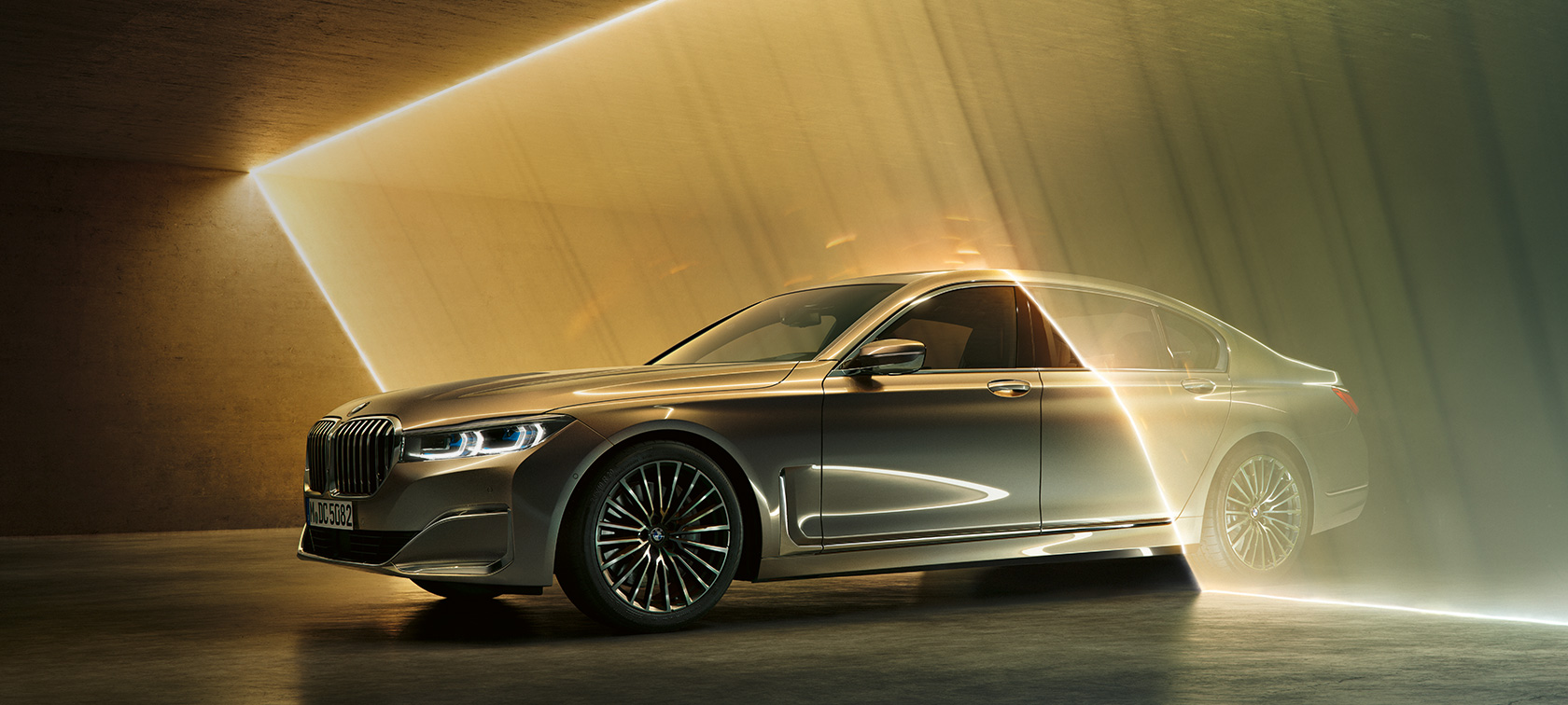BMW 7-sarjan Sedan, luksussedan, 3/4-näkymä edestä BMW 7-sarjan Sedan, luksussedan: harmaa BMW, josta näkyy kolme neljäsosaa edestä valon ympäröimänä