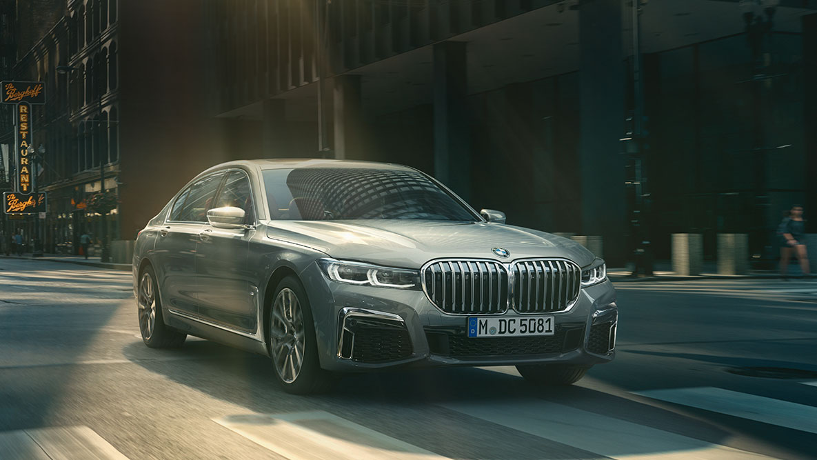 Driving Assistant Professional: Kuva, jossa näkyy kolme neljäsosaa BMW 7-sarjan Sedanista, joka ajaa kaupunkiympäristössä BMW 7-sarjan Sedanin Driving Assistant Professional