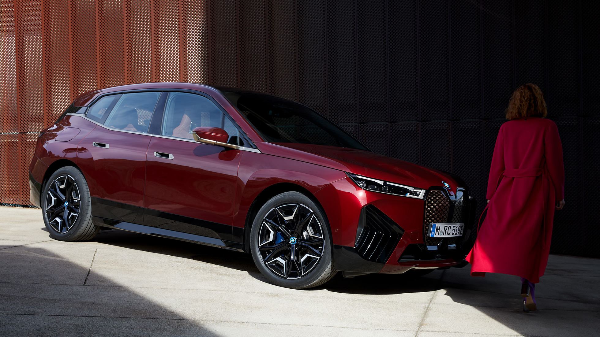 BMW iX, kolmen neljäsosan sivunäkymä, ulkopuoli BMW iX Aventurine Red i20, kolmen neljäsosan sivunäkymä, ulkopuoli