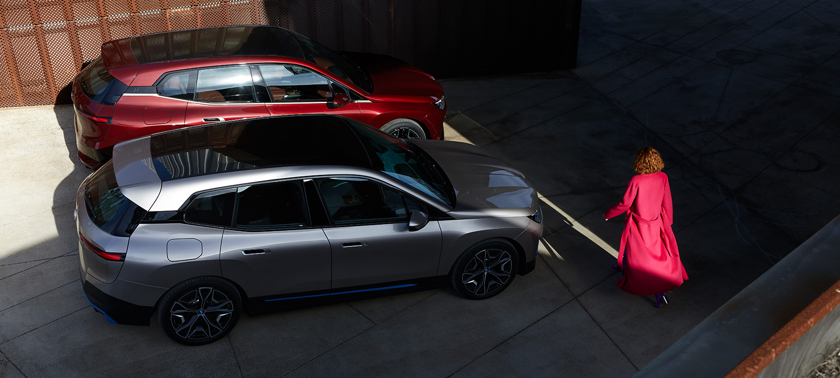 BMW iX lintuperspektiivistä mallin kanssa BMW iX Aventurine Red ja Cashmere Silver i20 lintuperspektiivistä mallin kanssa