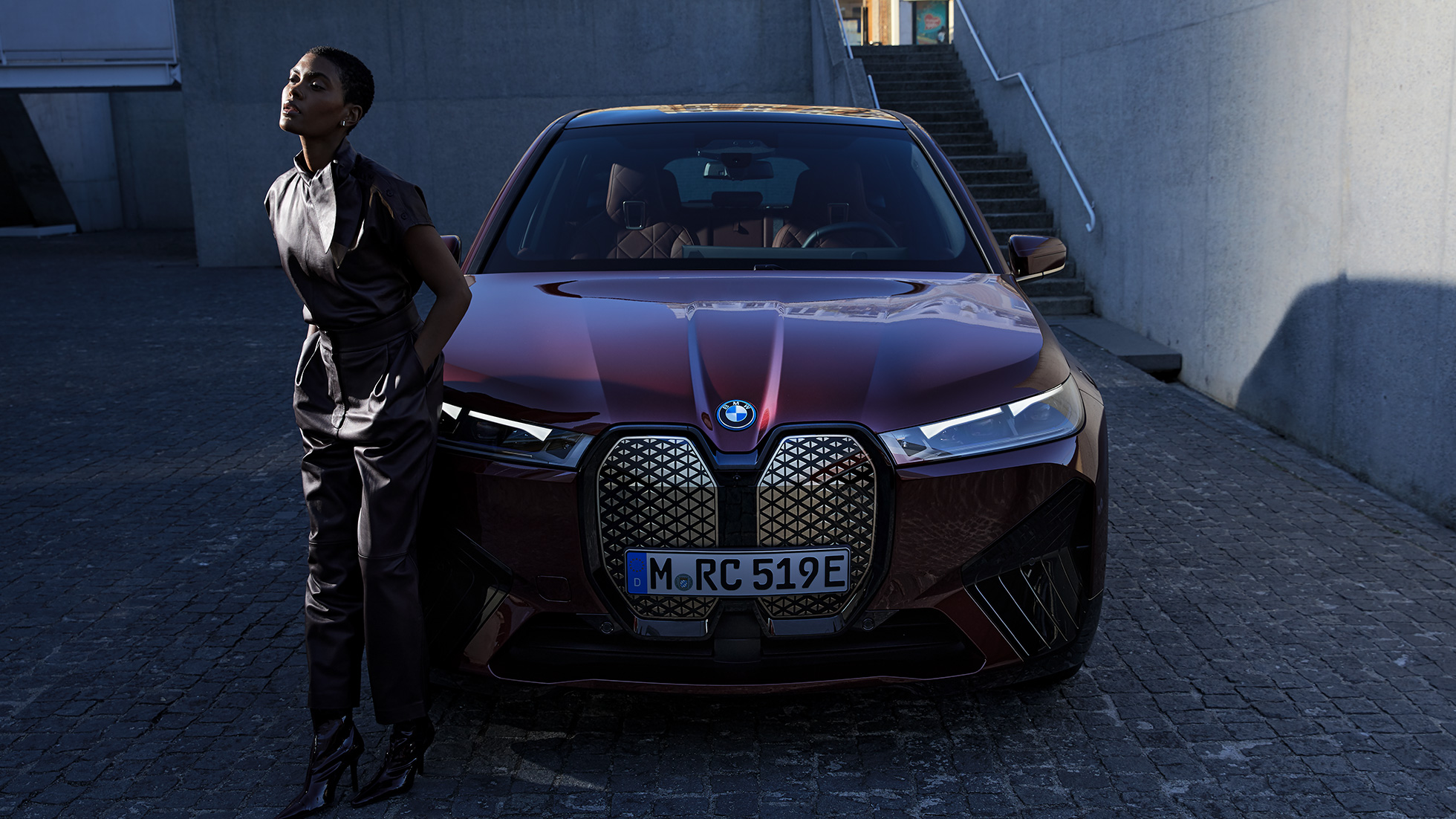 BMW iX, näkymä keulasta yhdessä mallin kanssa BMW iX Aventurine Red i20, näkymä keulasta yhdessä mallin kanssa
