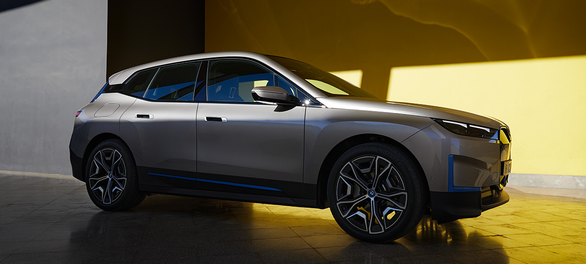 BMW iX, kolmen neljäsosan sivunäkymä pysähtyneenä olevasta autosta BMW iX Cashmere Silver i20, kolmen neljäsosan sivunäkymä pysähtyneenä olevasta autosta