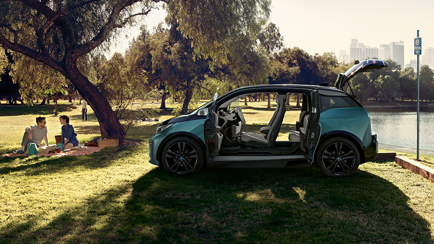BMW i3 2018 puistossa BMW i3 I01 2018 Jucaro Beige, korostuksella Frozen Grey -metalliväri, sivunäkymä avoimin ovin puistossa