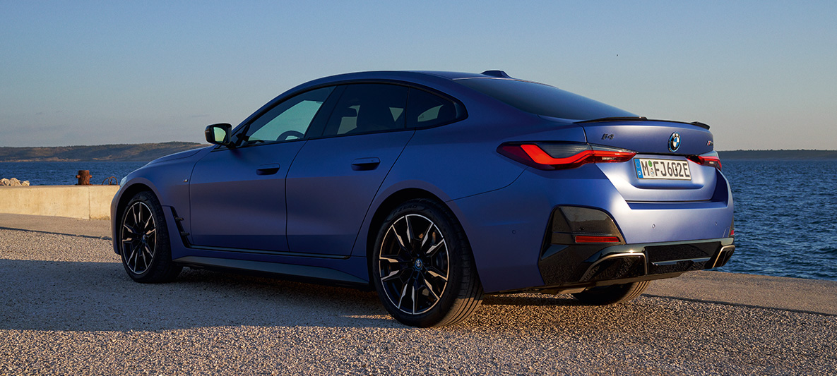 Kolmen neljäsosan näkymä perästä BMW i4 M50 G26 2021 BMW i4 M50 G26 2021 metalliväri M Portimao Blue, 3/4-näkymä perästä laiturilla