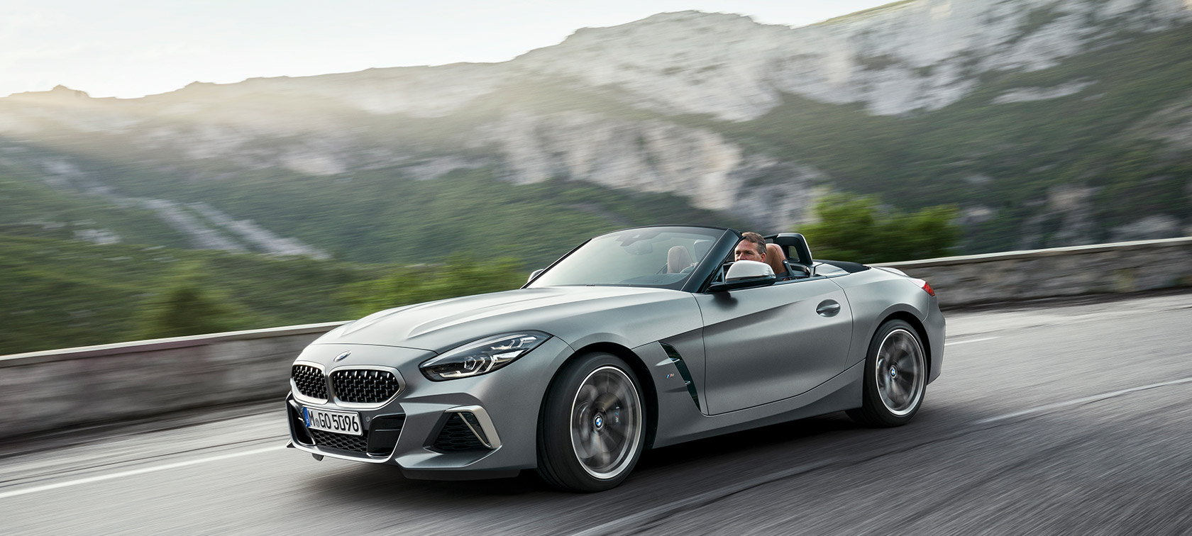 BMW Z4 M40i G29 liikkeellä vuoristomaiseman edessä BMW Z4 Roadster M40i G29 2019 Cabrio BMW Individual -metalliväri Frozen Grey, kolmen neljäsosan näkymä vuoristomaiseman edessä ajavan auton keulasta