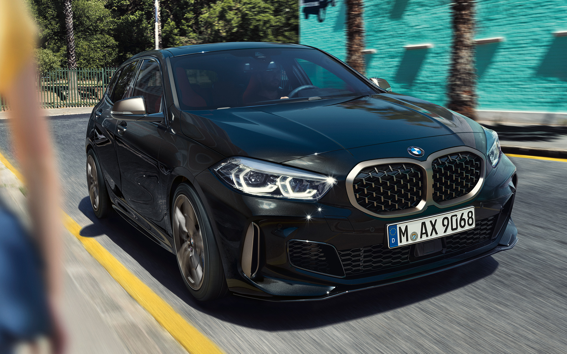 BMW M135i xDrive (F40), metallivärillä Black Sapphire, kolmen neljäsosan näkymä keulasta auton ollessa liikkeellä