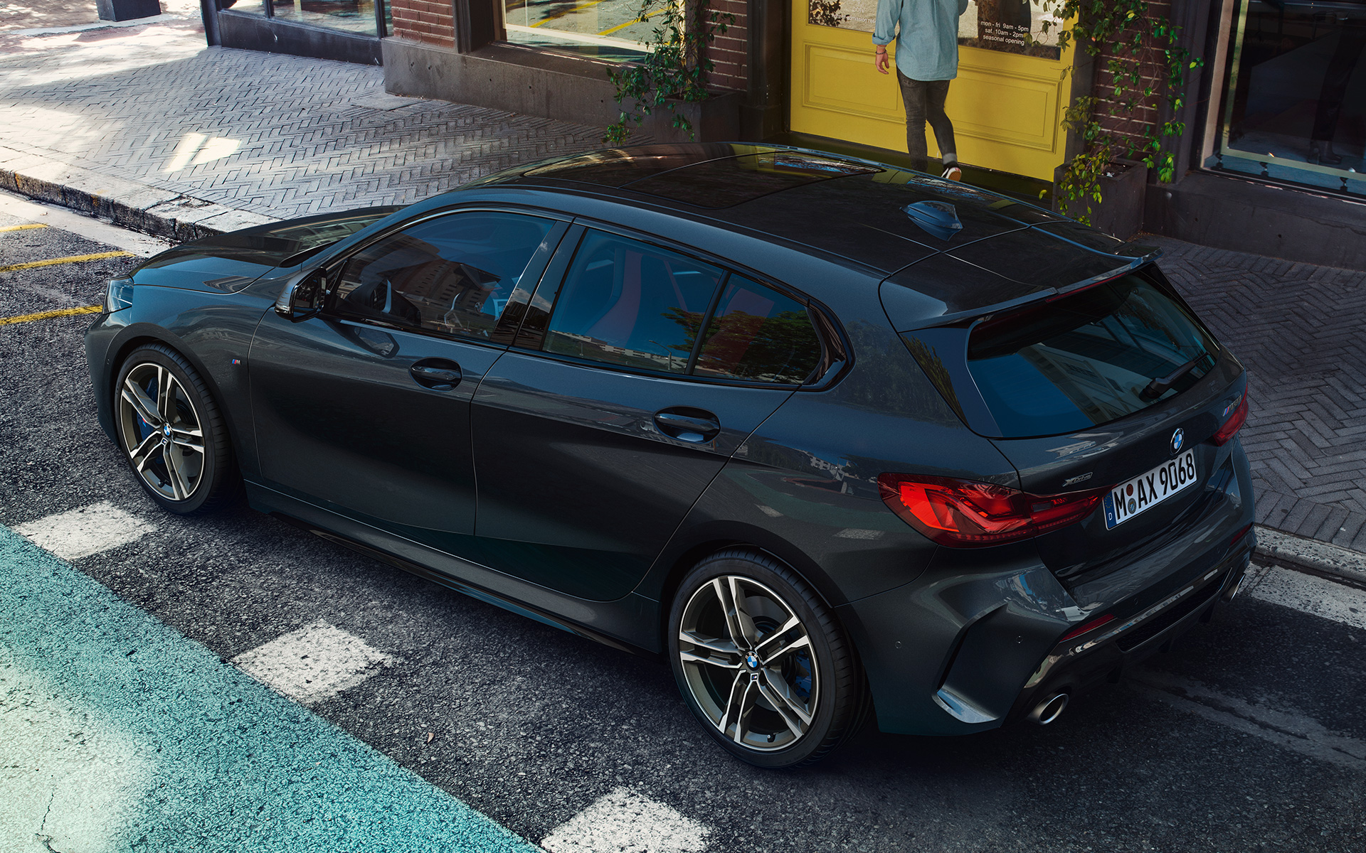 BMW M135i xDrive (F40), metallivärillä Black Sapphire, sivunäkymä lintuperspektiivistä auton ollessa pysäköitynä