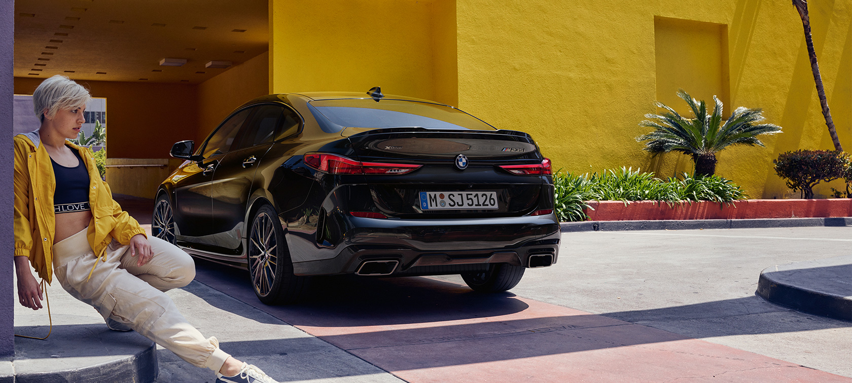 BMW M235i xDrive Gran Coupé, 3/4-näkymä perästä BMW M235i xDrive Gran Coupé metalliväri Black Sapphire F44, 3/4-näkymä perästä nainen etualalla