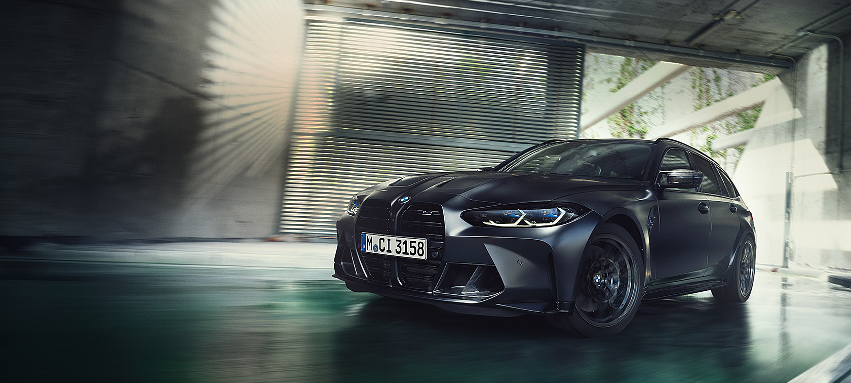 BMW M3 Competition Touring G81, BMW Individual Frozen Black -metalliväri 3/4-näkymä liikkeellä olevan auton keulasta