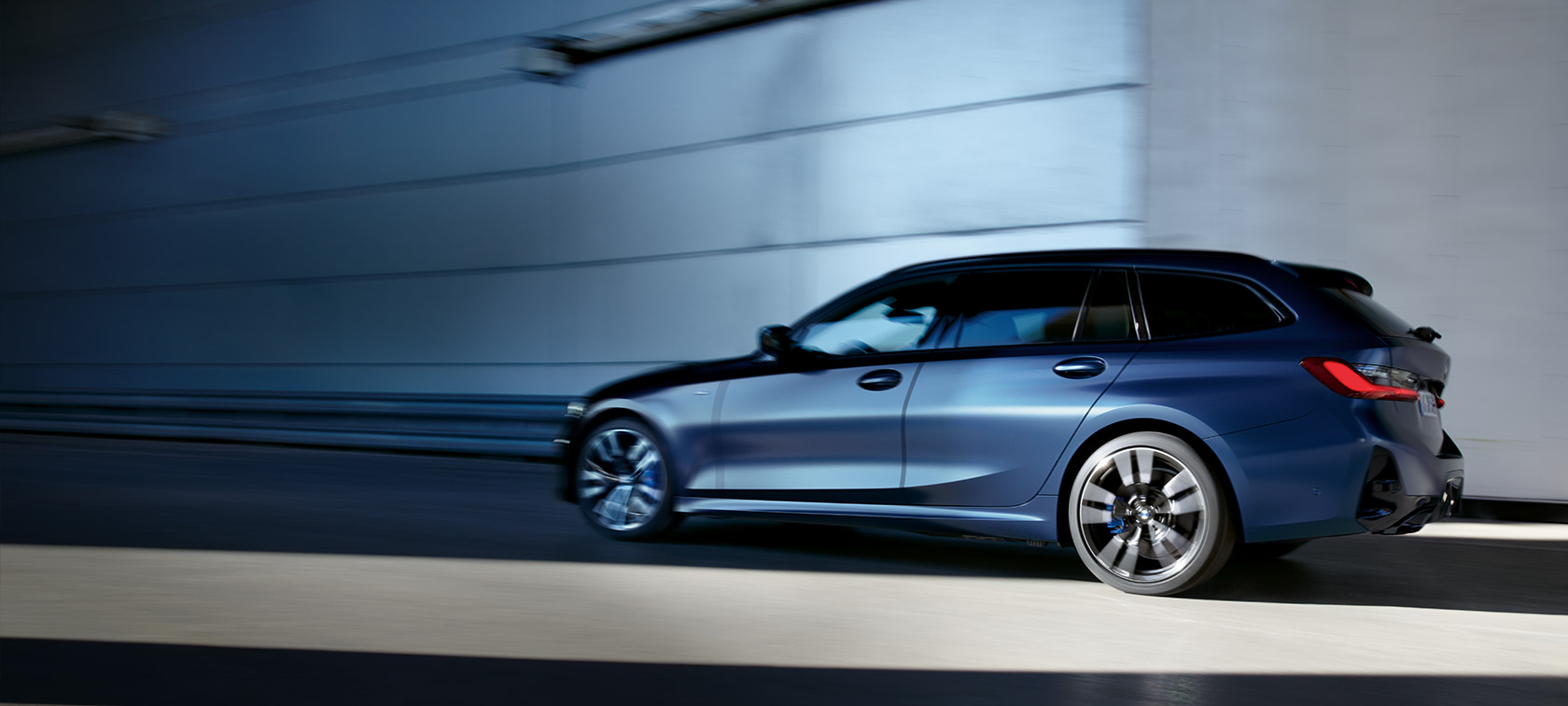 BMW M340i xDrive Touring G21, Frozen Tanzanite Blue, kolmen neljäsosan sivunäkymä liikkeellä olevasta autosta