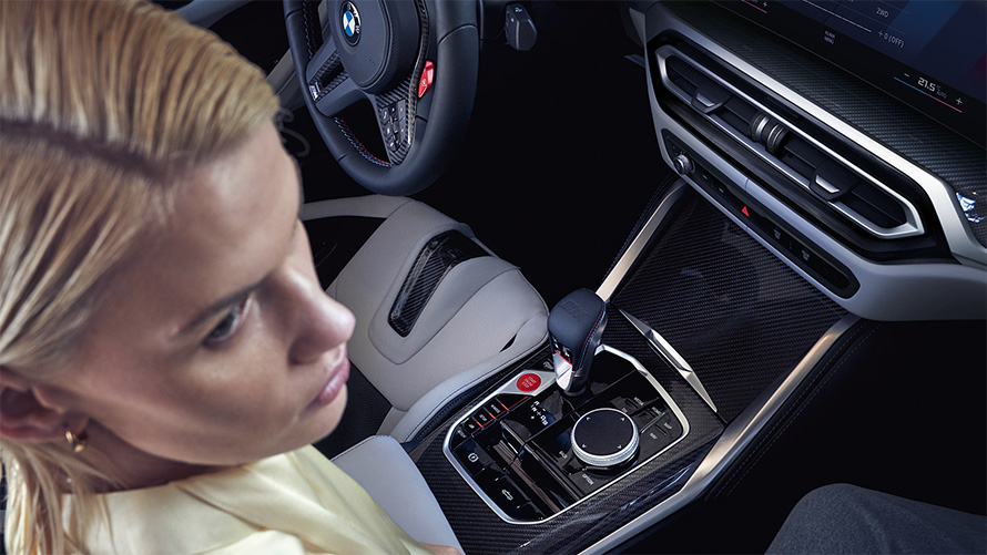 BMW M4 Competition Cabrio jossa M xDrive G83 sisätila 2021 keskikonsoli BMW M4 Competition Cabrio jossa M xDrive G83 2021 keskikonsoli ja nainen etumatkustajan paikalla