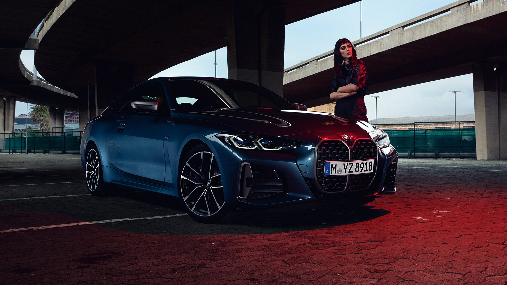 Malli seisoo BMW M440i xDrive Coupé G22 2020 -auton vieressä, kolmen neljäsosan sivunäkymä BMW M440i xDrive Coupé metalliväri Arctic Race Blue G22 2020, kuvassa kolmen neljäsosan sivunäkymä ja malli