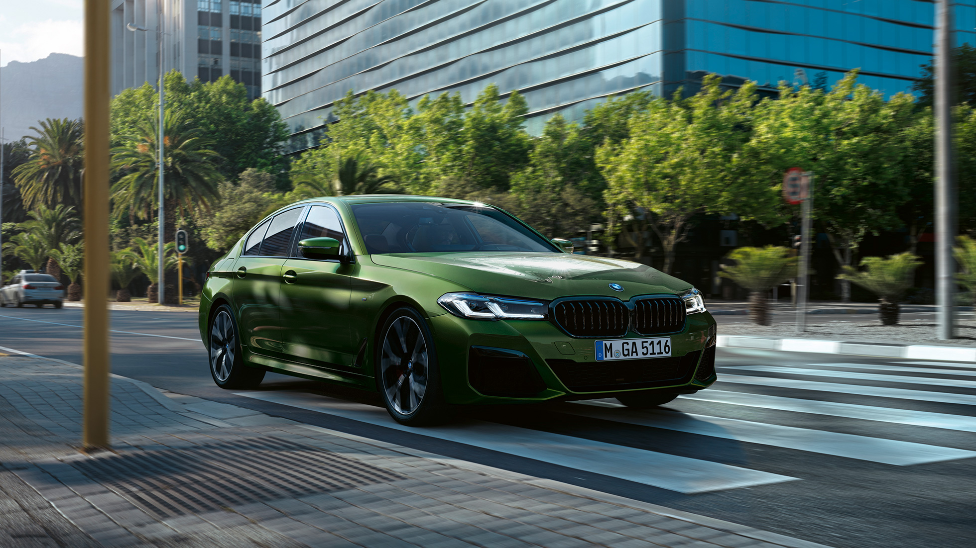 BMW M550i xDrive Sedan G30 LCI Facelift 2020 kolmen neljäsosan näkymä ajavan auton etuosasta BMW M550i xDrive Sedan G30 LCI Facelift 2020 BMW Individual metalliväri Verde Ermes kolmen neljäsosan näkymä kaupungissa ajavan auton etuosasta