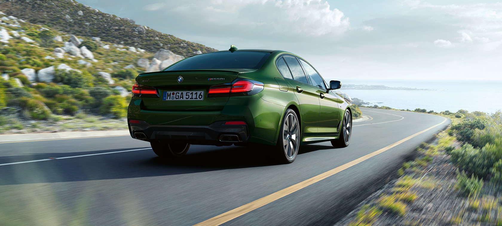 BMW M550i xDrive Sedan G30 LCI Facelift 2020 kolmen neljäsosan näkymä ajavan auton perästä BMW M550i xDrive Sedan G30 LCI Facelift 2020 BMW Individual metalliväri Verde Ermes kolmen neljäsosan näkymä ajavan auton perästä