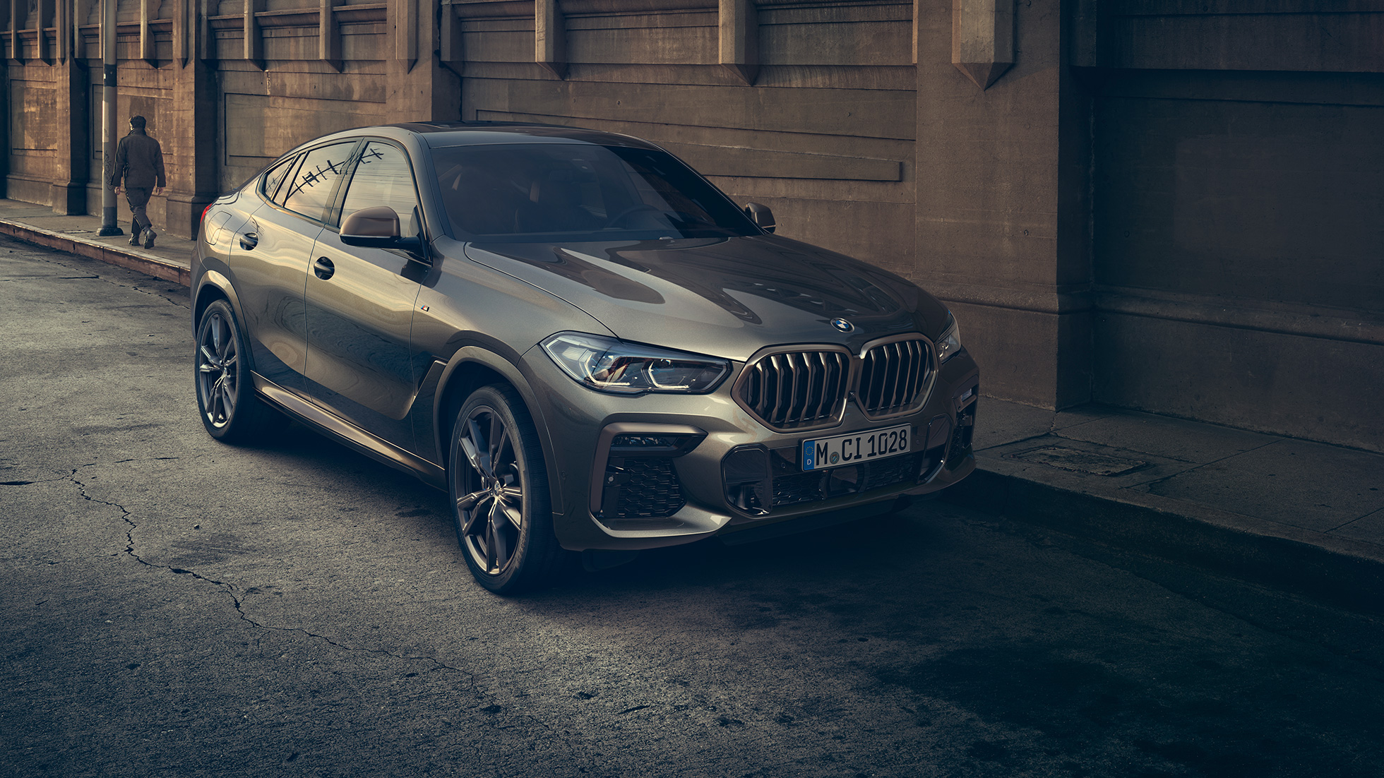 BMW X6 M50i pysähtyneenä. BMW X6 M50i, 3/4-näkymä edestä auton ollessa pysähtyneenä kaupunkinäkymän edessä.