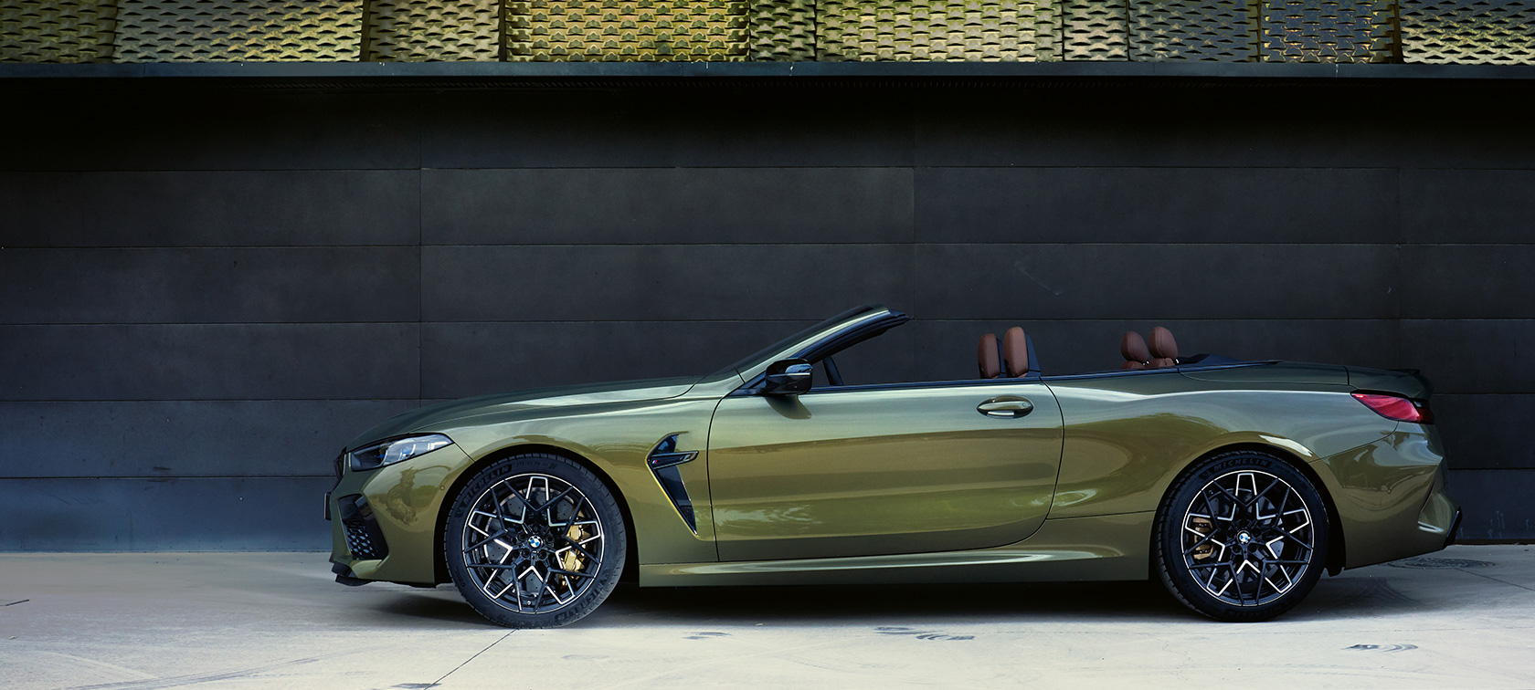 BMW M8 Competition Cabrio F91 LCI Facelift 2022, sivukuva pysähtyneenä olevasta autosta BMW M8 Competition Cabrio F91 LCI Facelift 2022 BMW Individual Brass metallic, sivukuva pysähtyneenä olevasta autosta, jossa on ovi auki, ja naismalli