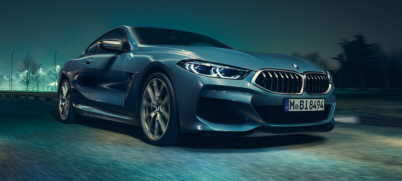 BMW M850i xDrive Coupé, 3/4-näkymä edestä. BMW M850i xDrive Coupé metallivärissä Barcelona Blue, 3/4-näkymä liikkeellä olevan auton etuosasta.