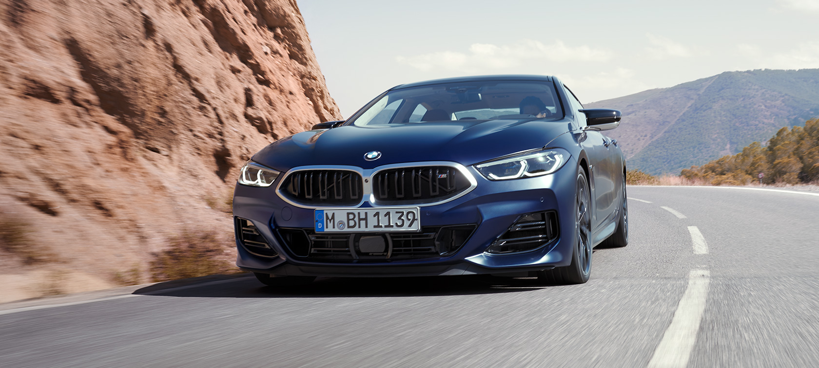 3/4-etunäkymä auton ajaessa BMW M850i xDrive Gran Coupé G16 LCI Facelift 2022 BMW M850i xDrive Gran Coupé G16 LCI Facelift 2022 BMW Individual Frozen Tanzanite Blue -metalliväri 3/4-näkymänä edestä auton ajaessa kaarteessa