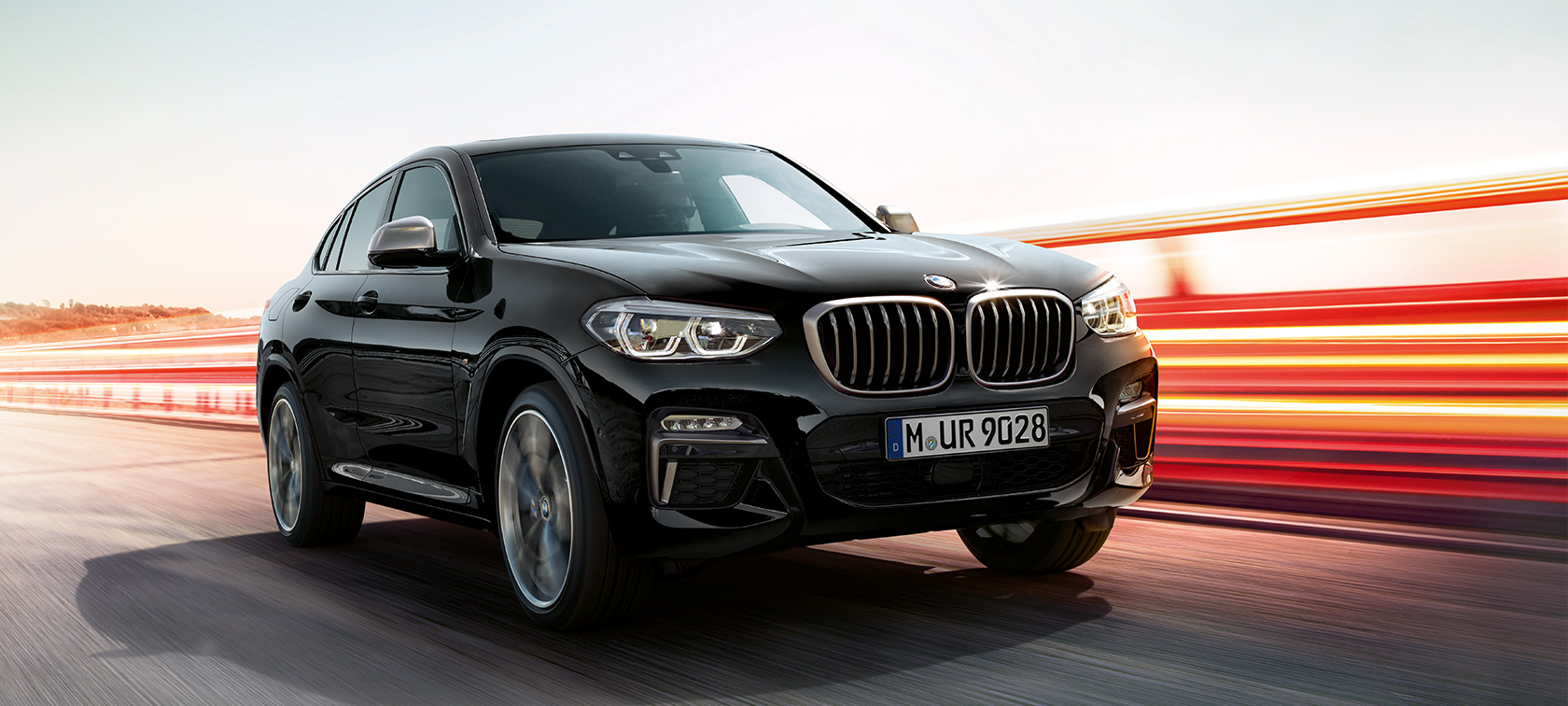 BMW X4 M40i ja BMW X4 M40d, kolme neljäsosaa näkymä edestä vasemmalta. BMW X4 M40i ja BMW X4 M40d,, metalliväri Sapphire Black, ajaa, ulkopuoli, kolme neljäsosaa näkymä edestä vasemmalta ja valot.