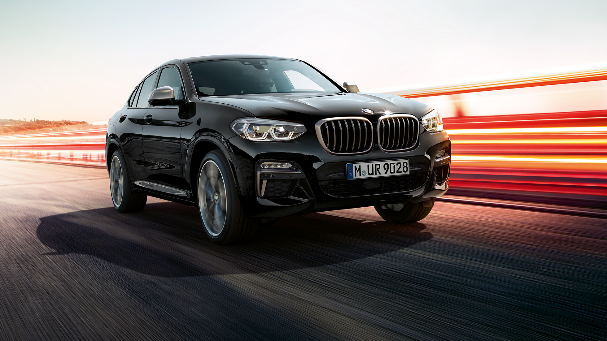 BMW X4 M40i ja BMW X4 M40d, kolme neljäsosaa näkymä edestä. BMW X4 M40i ja BMW X4 M40d, metalliväri Sapphire Black, ulkopuoli, kolme neljäsosaa näkymä edestä vasemmalta ja valot.