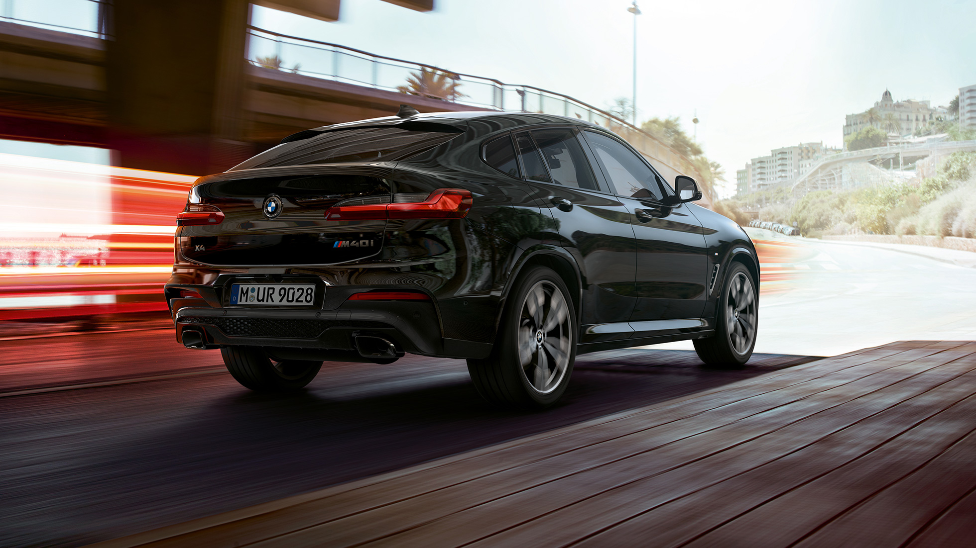 BMW X4 M40i, takaosasta näkyy kolme neljäsosaa. BMW X4 M40i metalliväri Sapphire Black, ulkopuoli, kolme neljäsosa näkymä takaa oikealta ja valot.